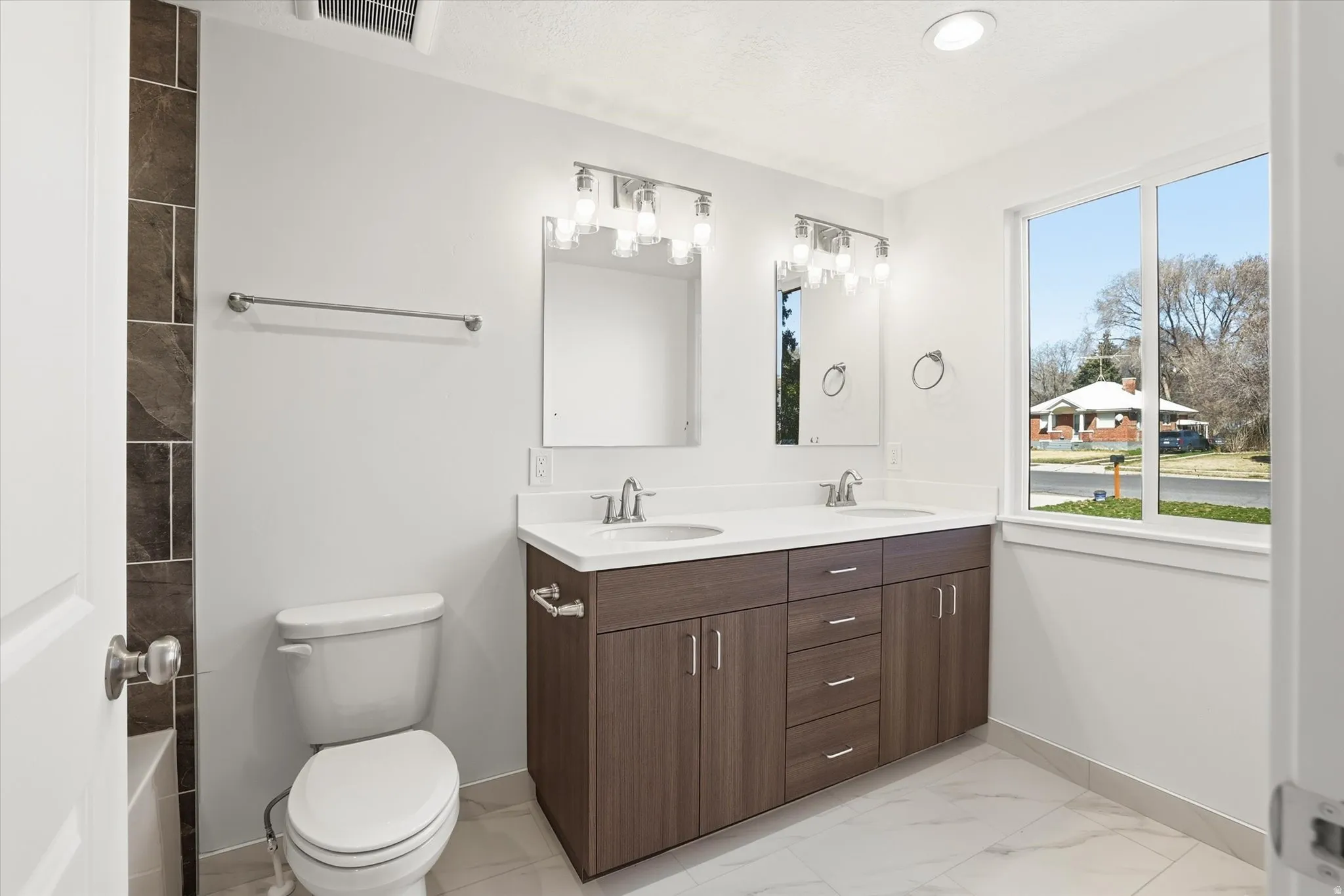 Primary Suite Full bathroom featuring double vanity, light marble finish flooring, and a tub to relax in