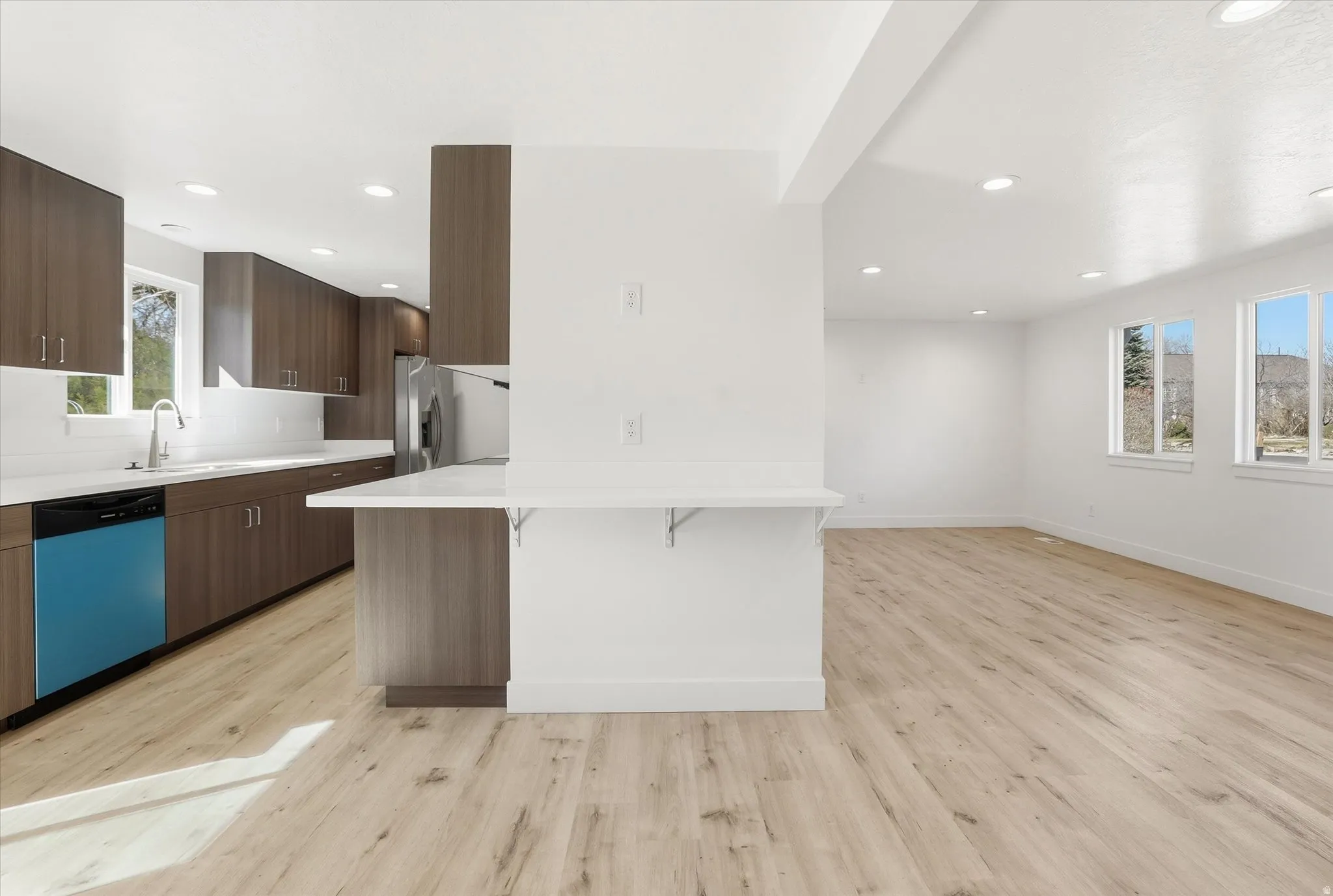 Kitchen with a breakfast bar area, dishwashing machine, a peninsula, light wood-style floors, and modern cabinets