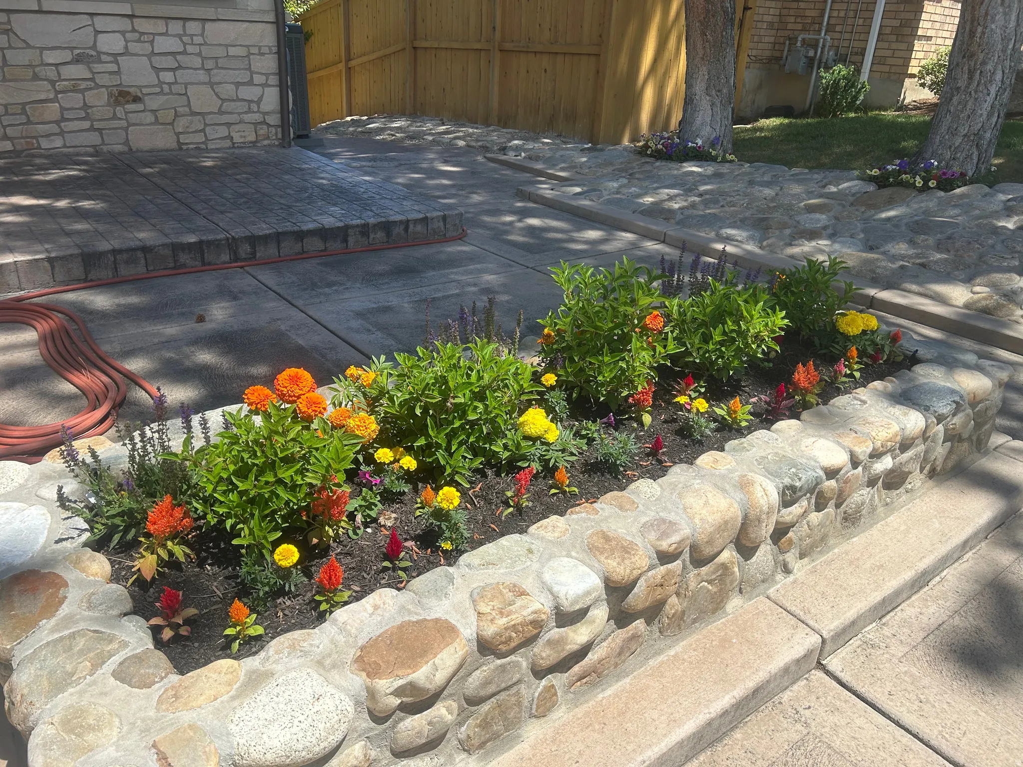 Stone-clad raised garden bed featuring diverse colorful plantings