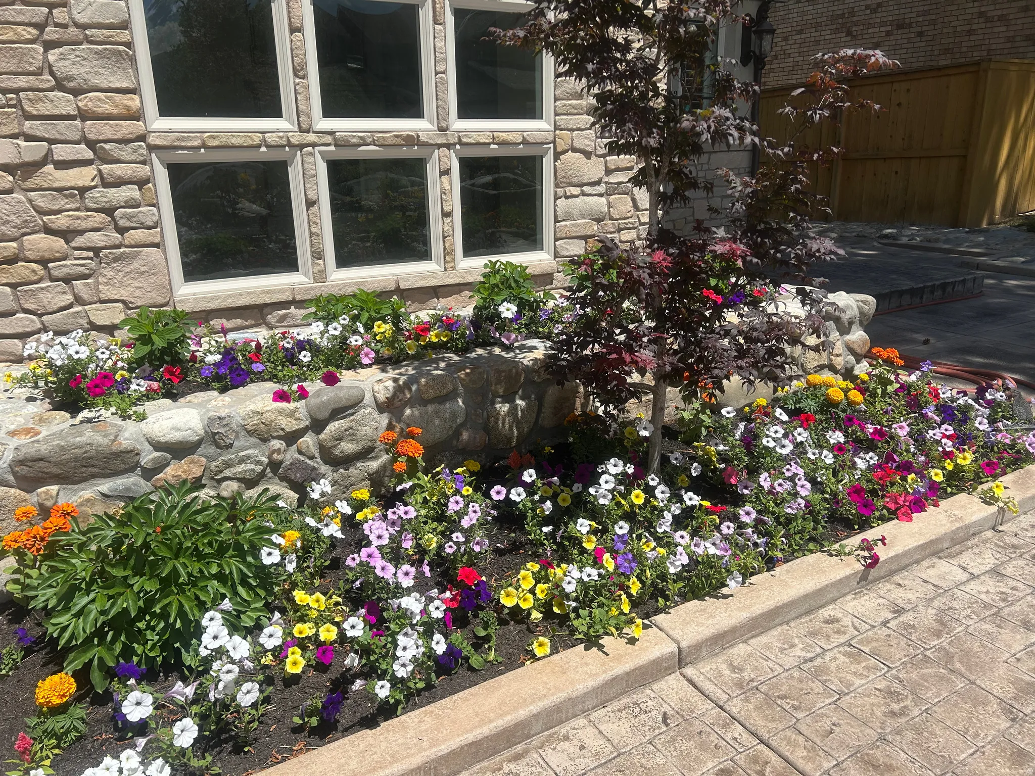 Stone facade with multi-pane windows and a vibrant floral garden