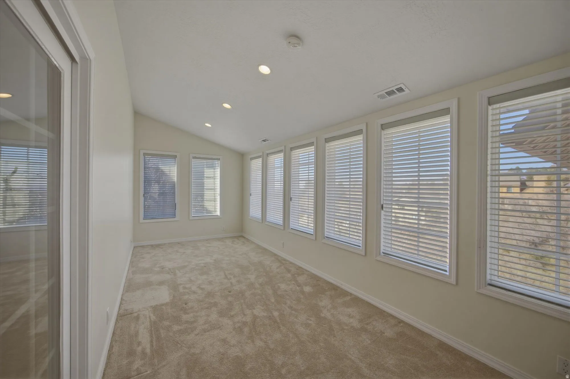 Unfurnished sunroom featuring lofted ceiling and healthy amount of natural light connected to main floor primary bedroom.