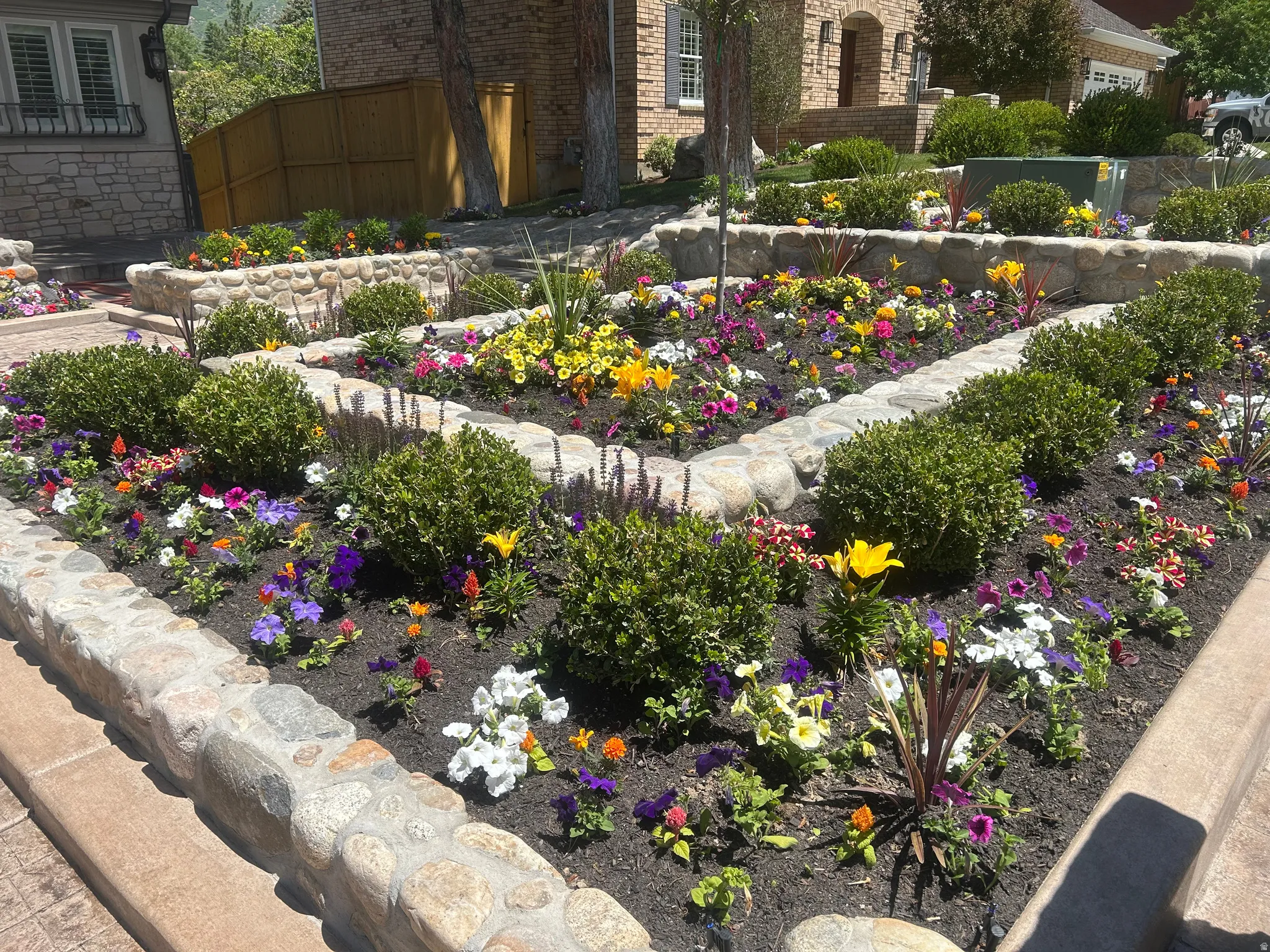 Tiered landscaping featuring stone retaining walls, diverse flowering plants, and established shrubbery