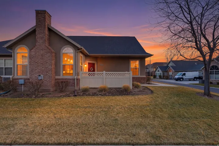 View of front of home with stucco siding, a front lawn, a porch, a chimney, and roof with shingles