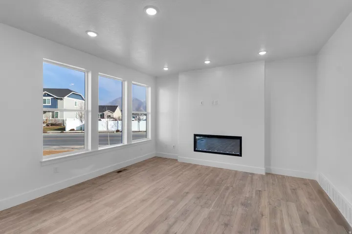 Unfurnished living room with a glass covered fireplace, light wood-type flooring, and recessed lighting