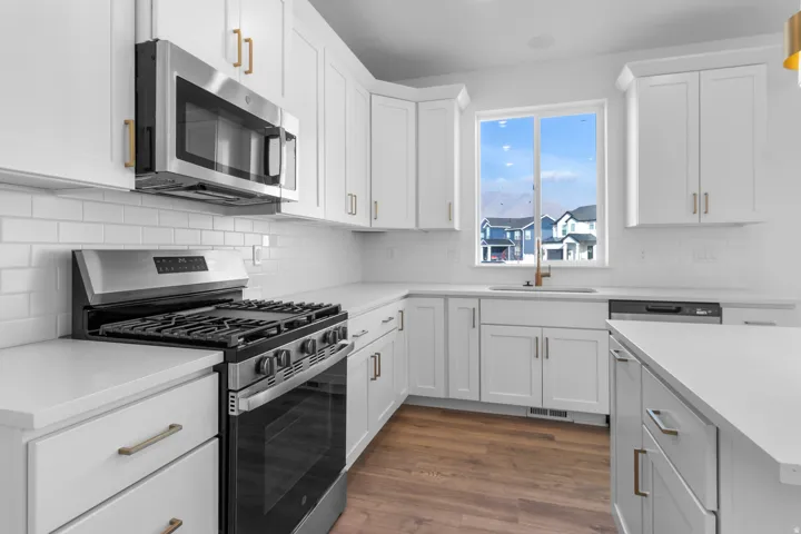 Kitchen with stainless steel appliances, white cabinetry, dark wood finished floors, decorative backsplash, and light stone counters