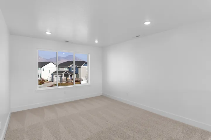 Empty room with light colored carpet and recessed lighting