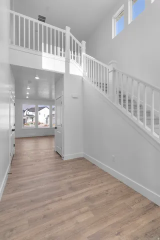 Unfurnished living room featuring healthy amount of natural light, a high ceiling, and wood finished floors