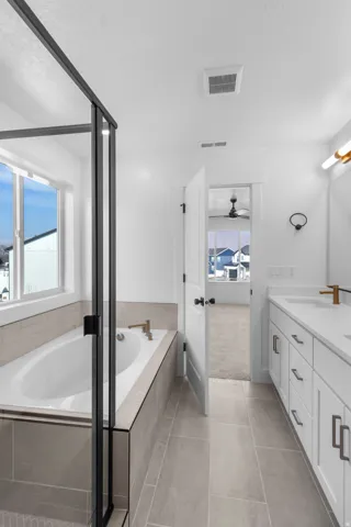 Bathroom with a garden tub, double vanity, light tile patterned floors, and light colored carpet