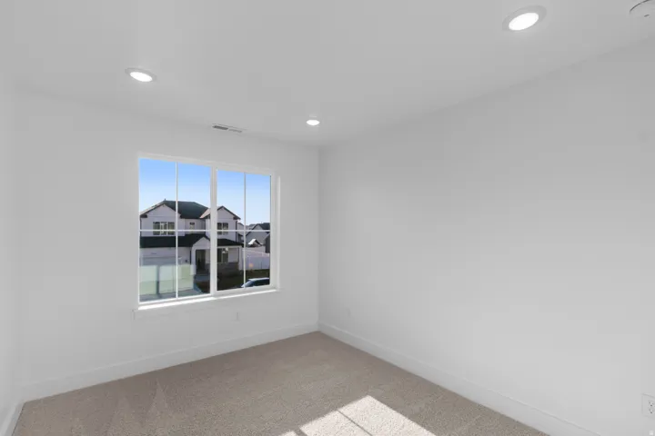 Empty room with light colored carpet and recessed lighting