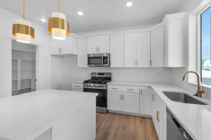 Kitchen with stainless steel appliances, white cabinets, light wood finished floors, light stone countertops, and backsplash
