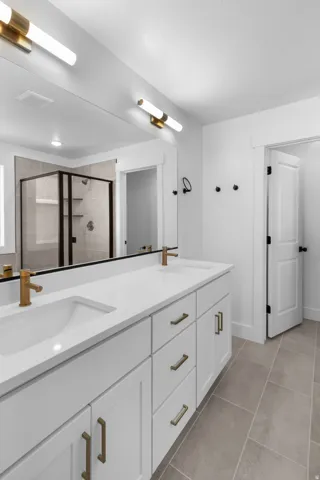 Bathroom featuring double vanity, a stall shower, and light tile patterned flooring