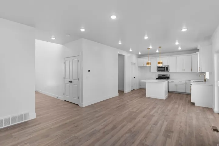 Kitchen with a kitchen island, stainless steel appliances, white cabinetry, light wood-style floors, and open floor plan