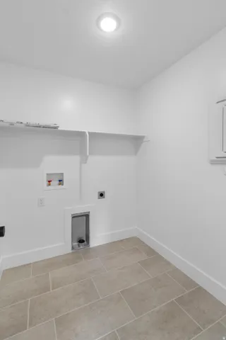 Laundry area with hookup for an electric dryer, washer hookup, and light tile patterned flooring