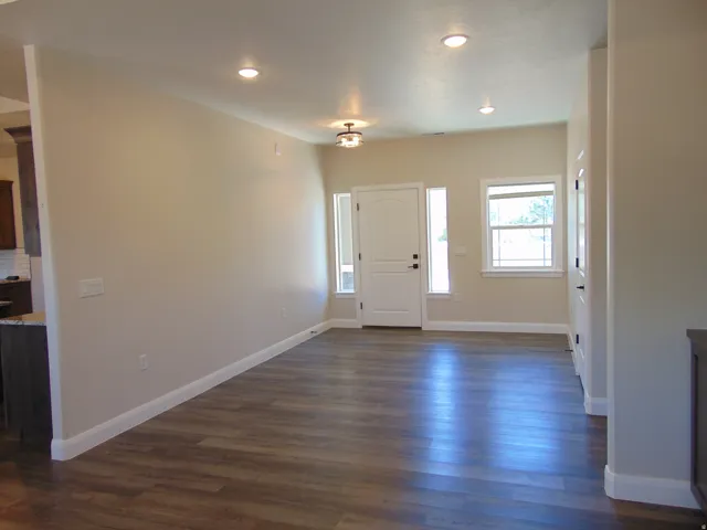 Spacious living area featuring wood-finish flooring, recessed lighting, and a neutral color palette