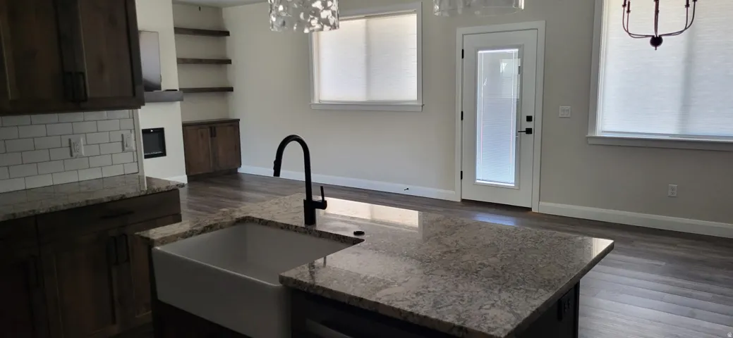 Spacious kitchen island with a farmhouse sink and dark faucet, complemented by wood-finish flooring