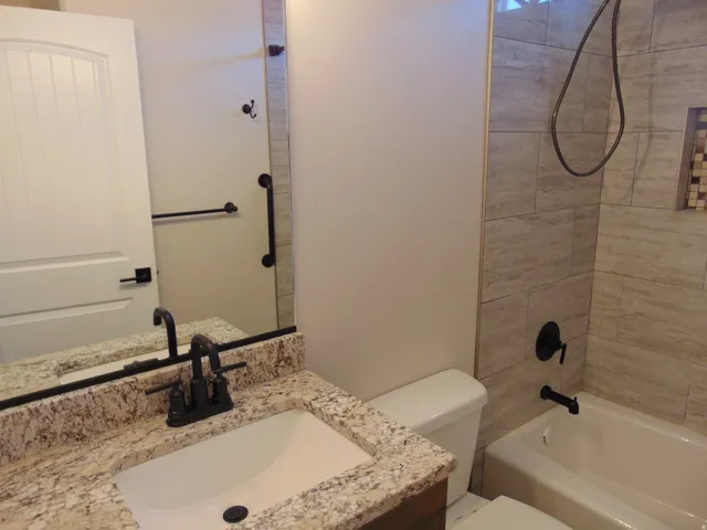 Bathroom featuring a granite-finish vanity, undermount sink, and matte black fixtures
