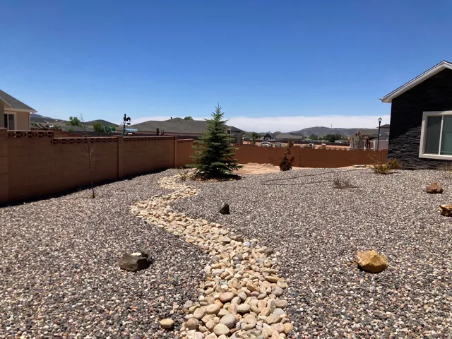 Expansive backyard featuring a river rock dry creek bed, decorative gravel landscaping, and a mature evergreen