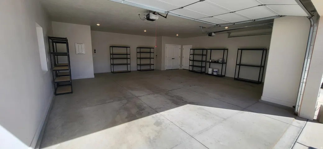 Spacious garage with concrete flooring, recessed lighting, and white overhead garage doors