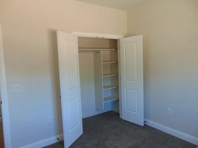 Built-in closet with bifold doors, integrated shelving, and hanging rod