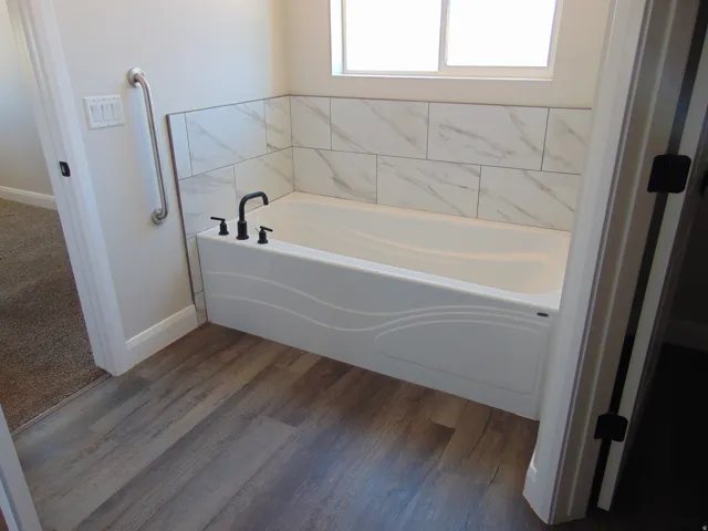 Bathtub with white surround and patterned tile wainscoting