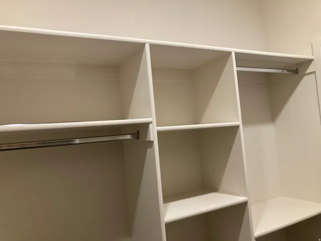 Built-in closet system with multiple shelves and chrome hanging rods