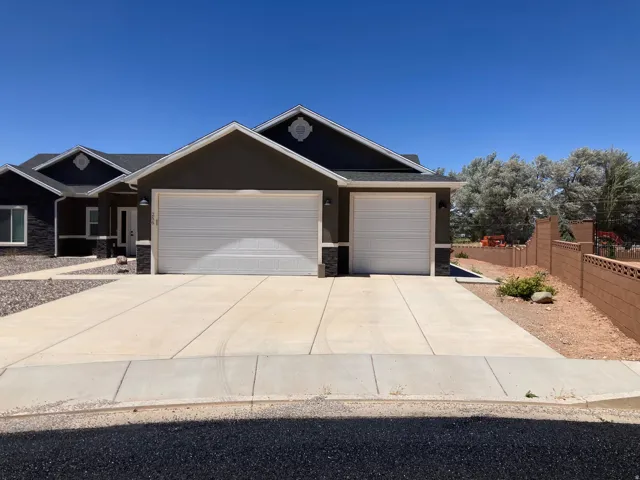 Contemporary single-story exterior featuring a two-car garage, dark stucco siding, and stone accents