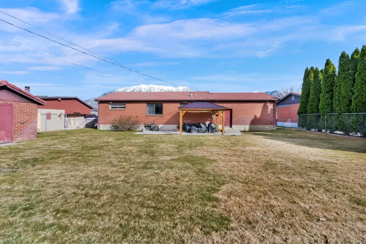 Back of property featuring a gazebo, brick siding, a fenced backyard, and a patio