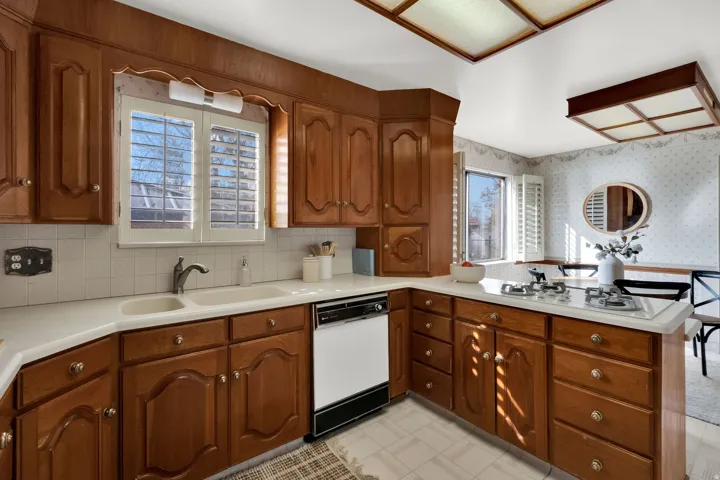 Kitchen featuring a peninsula, light countertops, wood finish cabinetry, and wallpapered walls