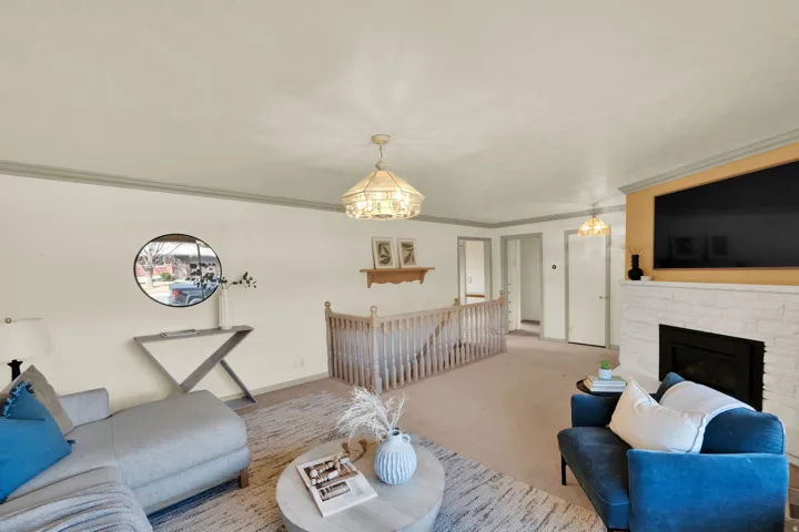 Carpeted living area with a fireplace, crown molding, and hanging lights