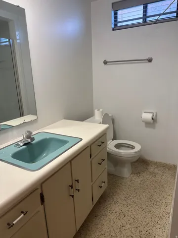Vanity with integrated sink, toilet, towel bar, and window with blinds