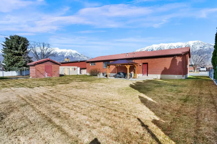 Rear view of house with a storage shed, a gazebo, a patio area, brick siding, and a mountain view
