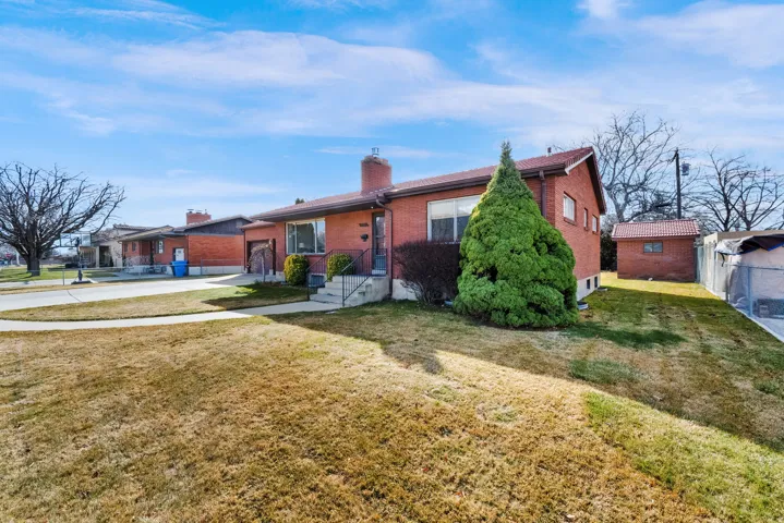 View of front of property featuring brick siding, a garage, a chimney, and driveway