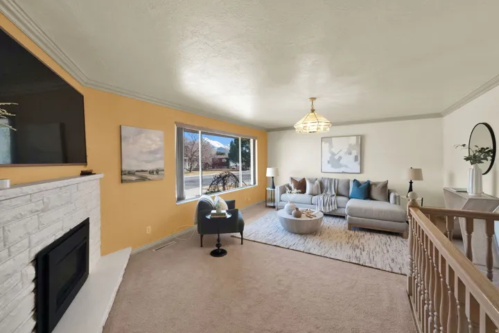 Carpeted living area featuring crown molding, a glass covered fireplace, hanging lights, and a textured ceiling