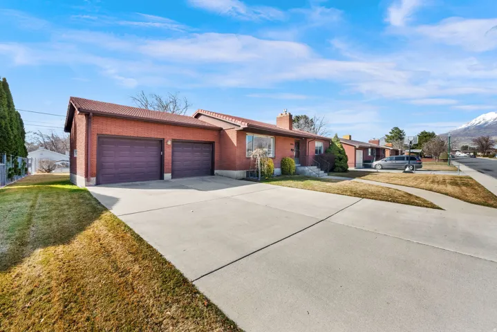 Ranch-style house featuring brick siding, a garage, driveway, and a front lawn