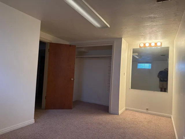 Carpeted interior space with a closet, built-in mirror, and wall-mounted vanity lighting