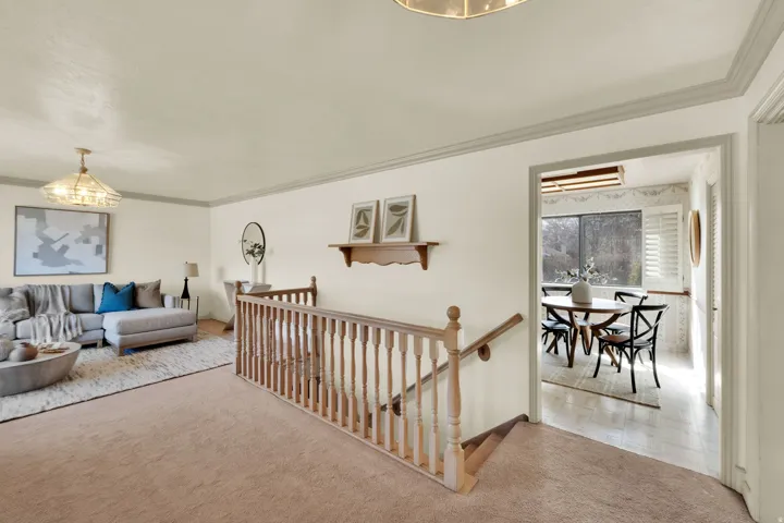 Living area with hanging lights, carpet floors, and ornamental molding