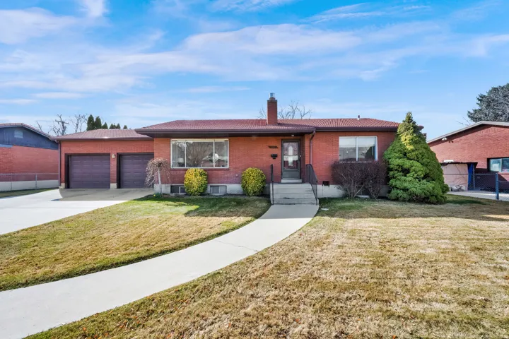 Ranch-style house featuring brick siding, a chimney, concrete driveway, and a garage
