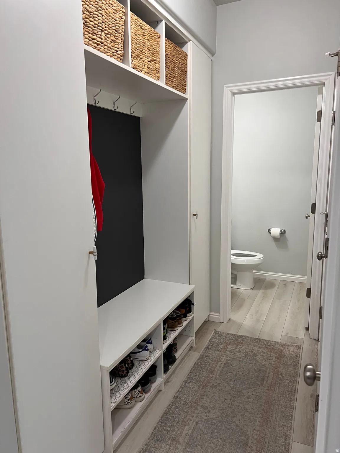 Mudroom featuring custom cabinets, light wood finished floors and baseboards