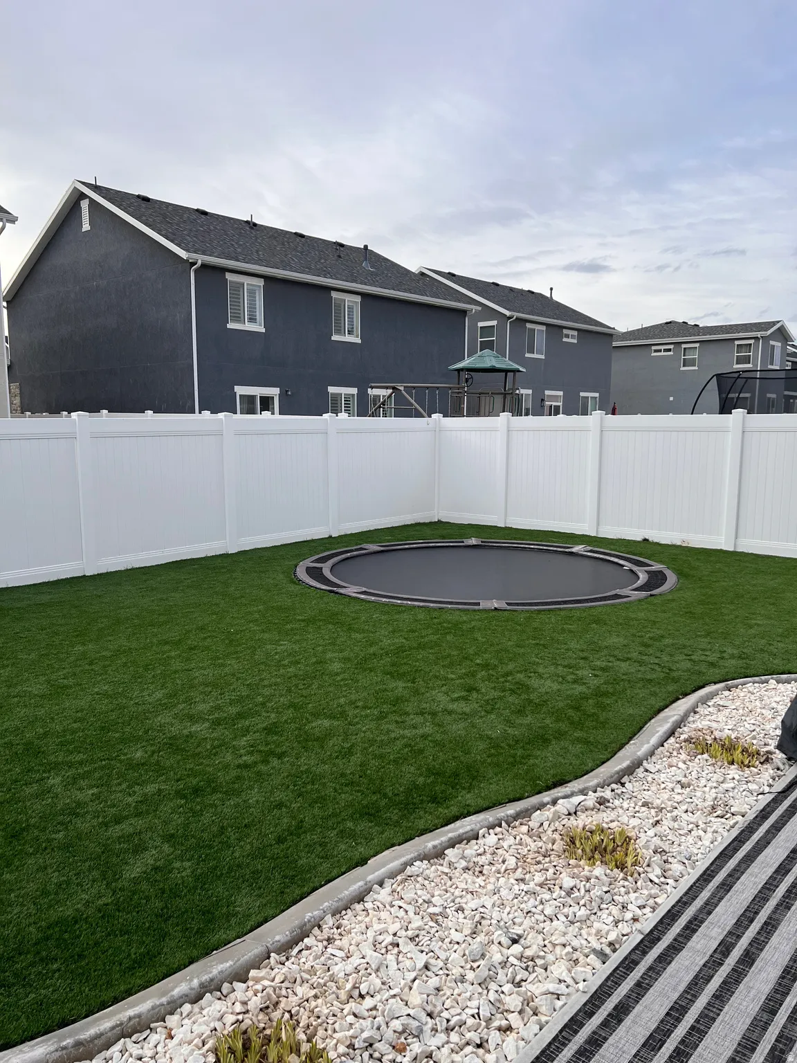 Fenced backyard featuring a trampoline