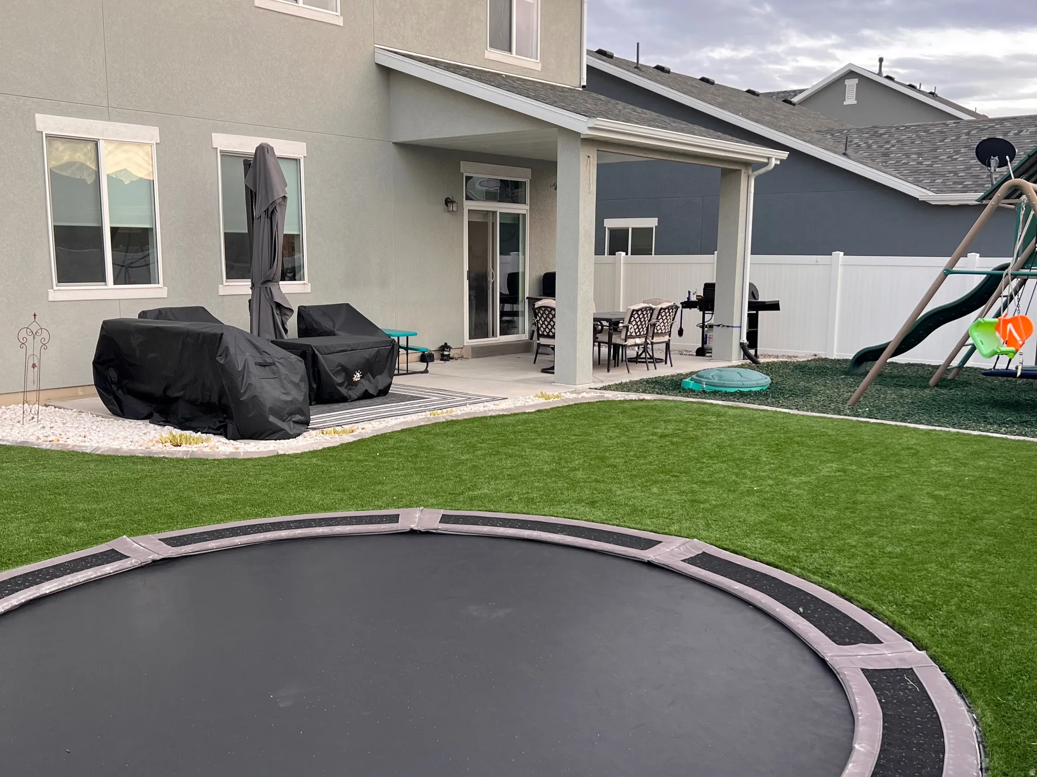 Back of property featuring a patio area, a trampoline, stucco siding, and a playground
