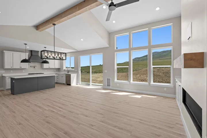 Unfurnished living room with ceiling fan, light wood-style floors, a fireplace, and suspended lighting