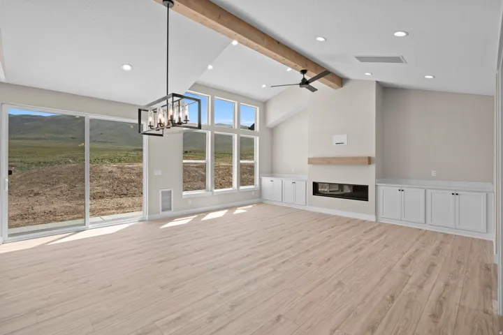 Unfurnished living room featuring hanging lights, ceiling fan, light wood-style flooring, and a glass covered fireplace
