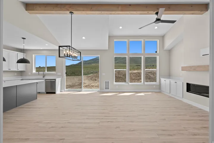 Unfurnished living room with suspended lighting, ceiling fan, light wood finished floors, a glass covered fireplace, and a mountain view