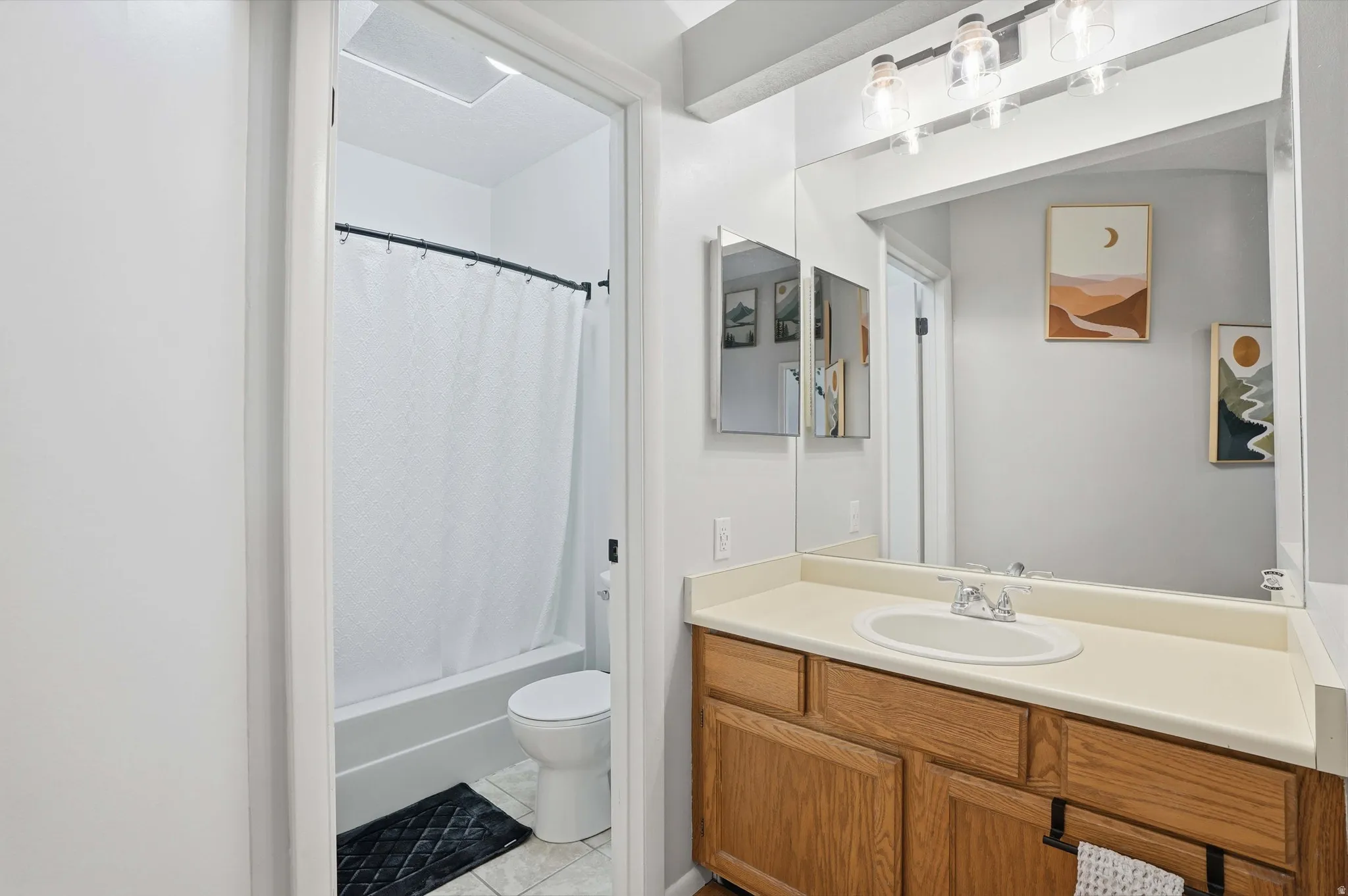 Bathroom featuring vanity, shower / tub combo with curtain, and light tile patterned flooring