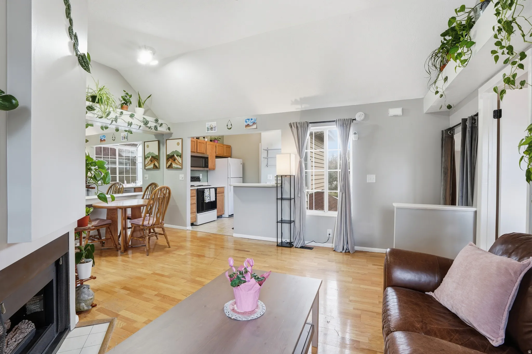 Living room featuring light wood-type flooring, lofted ceiling, and a fireplace with flush hearth