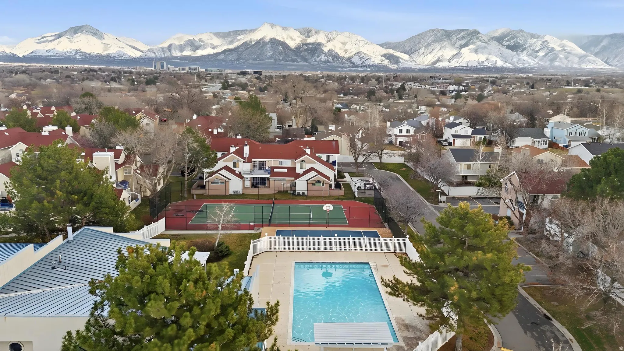 Aerial perspective of suburban area featuring a mountain backdrop and a pool area