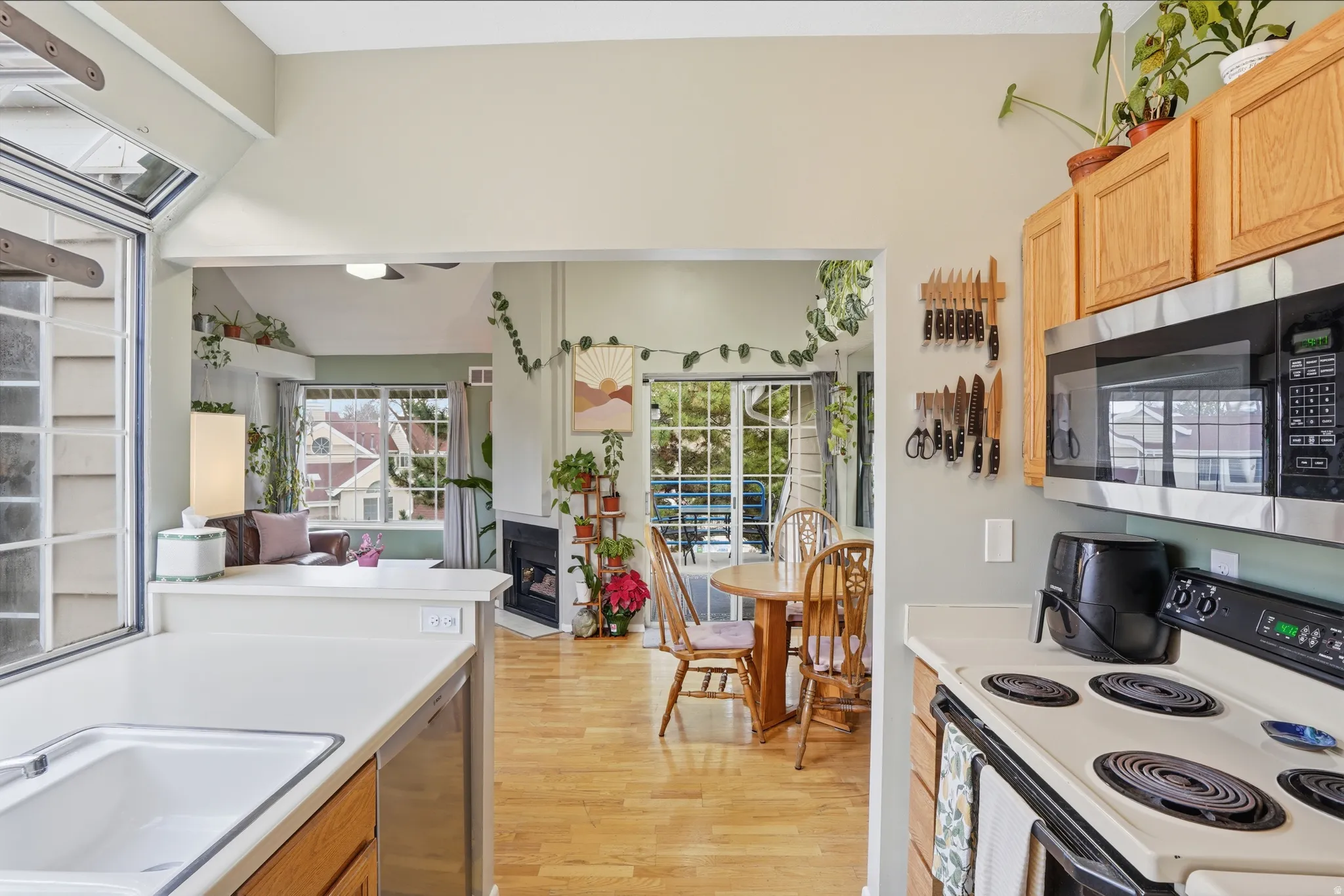 Kitchen with stainless steel appliances, light countertops, light wood finished floors, and a fireplace