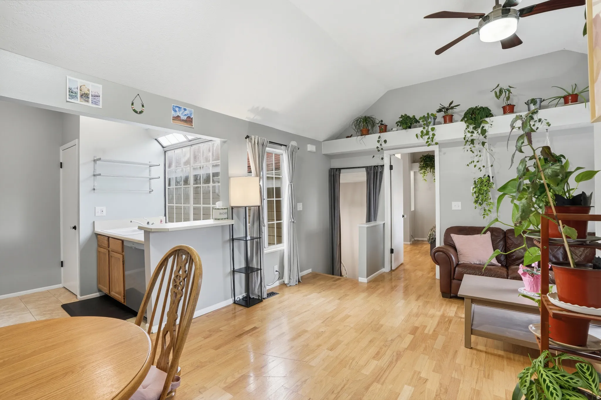 Living area featuring vaulted ceiling, a ceiling fan, and light wood finished floors