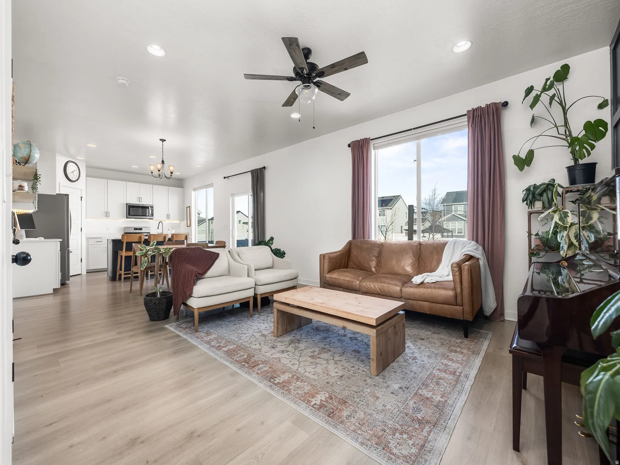 Living area with a chandelier, light wood finished floors, a ceiling fan, and plenty of natural light