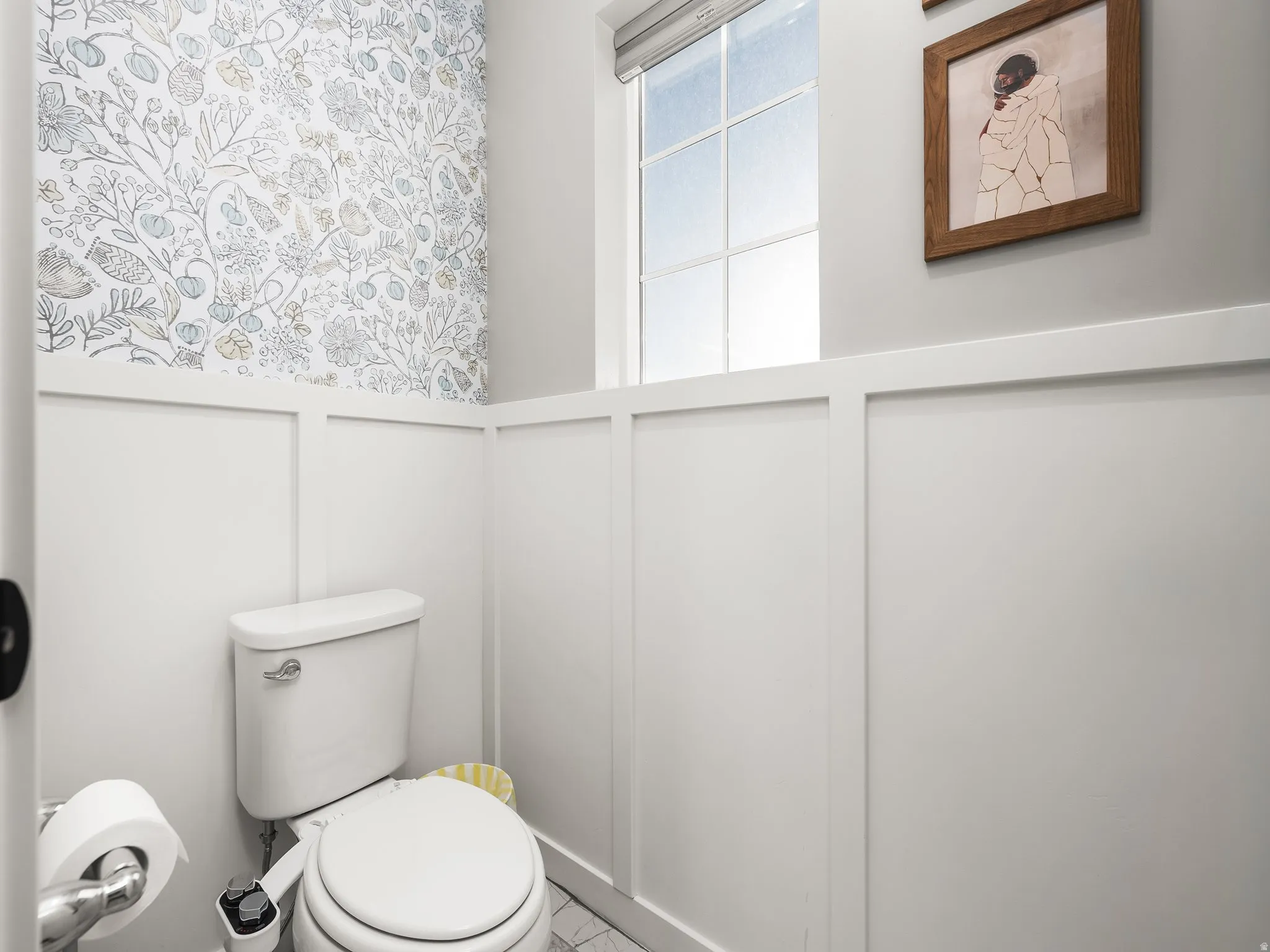Half bath featuring a decorative wall and a wainscoted wall